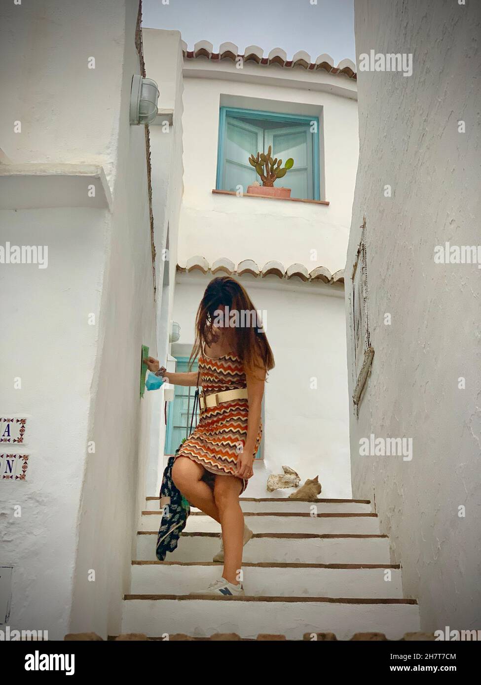 Brunette fille avec de longs cheveux et robe d'été marchant dans les jolies rues de Frigiliana, Malaga, Espagne Banque D'Images