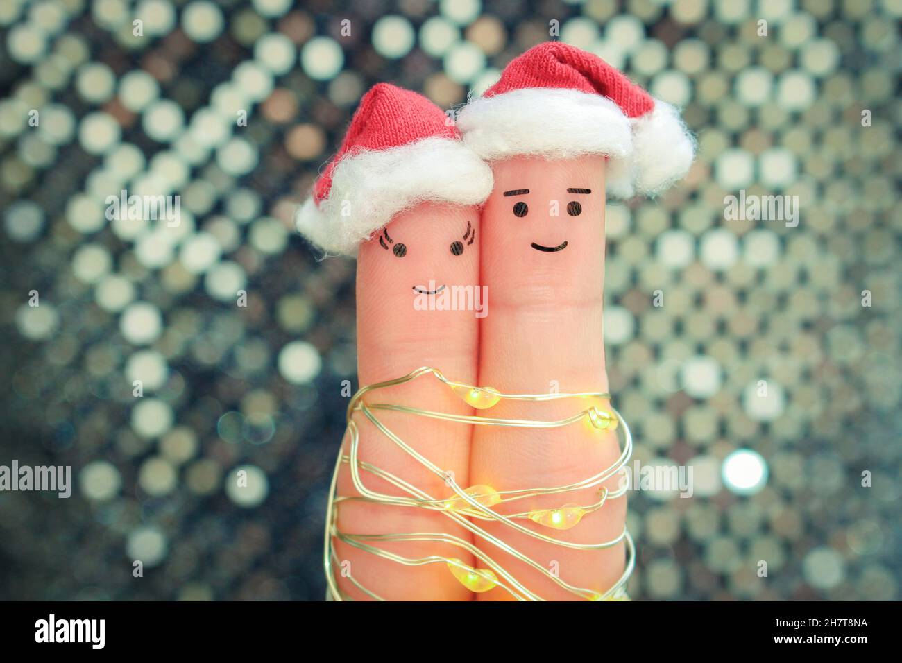 Fingers art of couple fête Noël.Concept de l'homme et de la femme riant dans les chapeaux du nouvel an. Banque D'Images