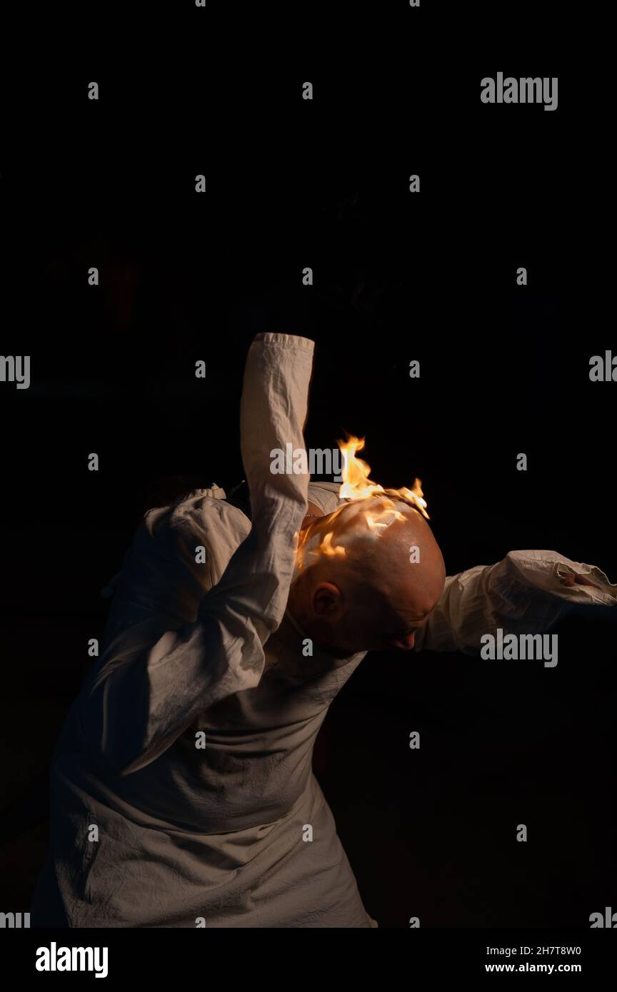 Homme chauve dans un blouson avec une tête brûlante sur un fond sombre. Banque D'Images