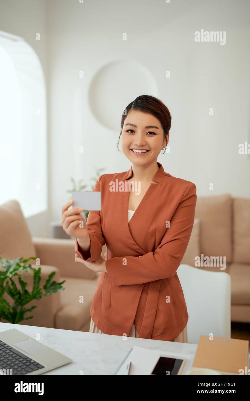 Une femme d'affaires présente une carte blanche vierge au bureau. Banque D'Images