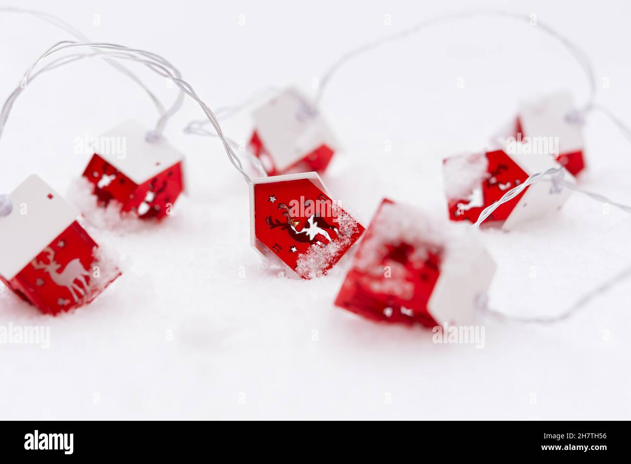Guirlande de Noël neige rouge.Carte postale horizontale colorée de Noël.Le concept d'une ambiance festive.Une guirlande en bois avec des cerfs sous la forme d'une maison o Banque D'Images