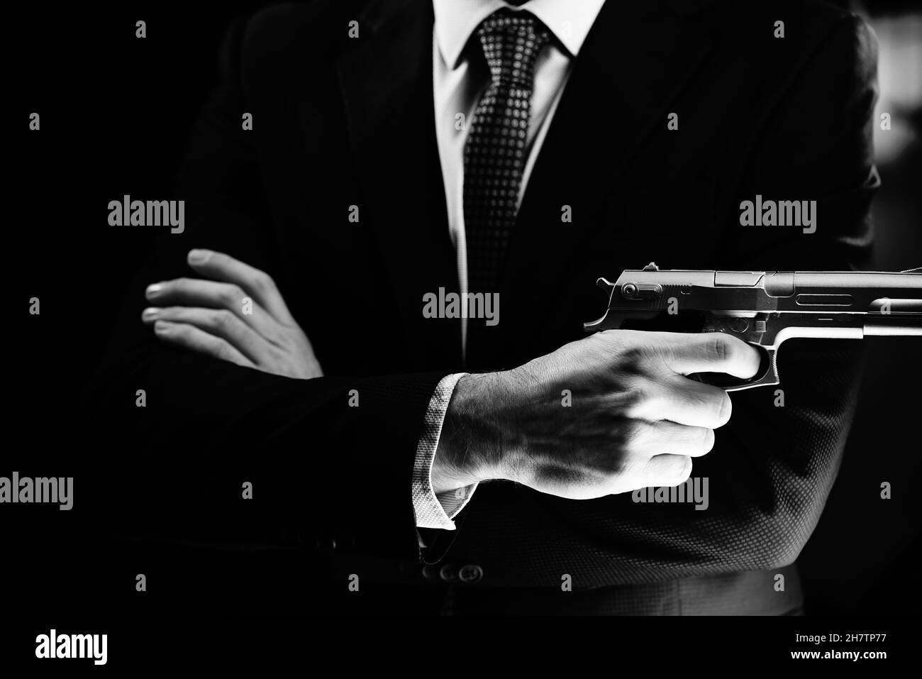 Homme bien habillé agent secret détective espion port combinaison et cravate tenant pistolet automatique. Banque D'Images