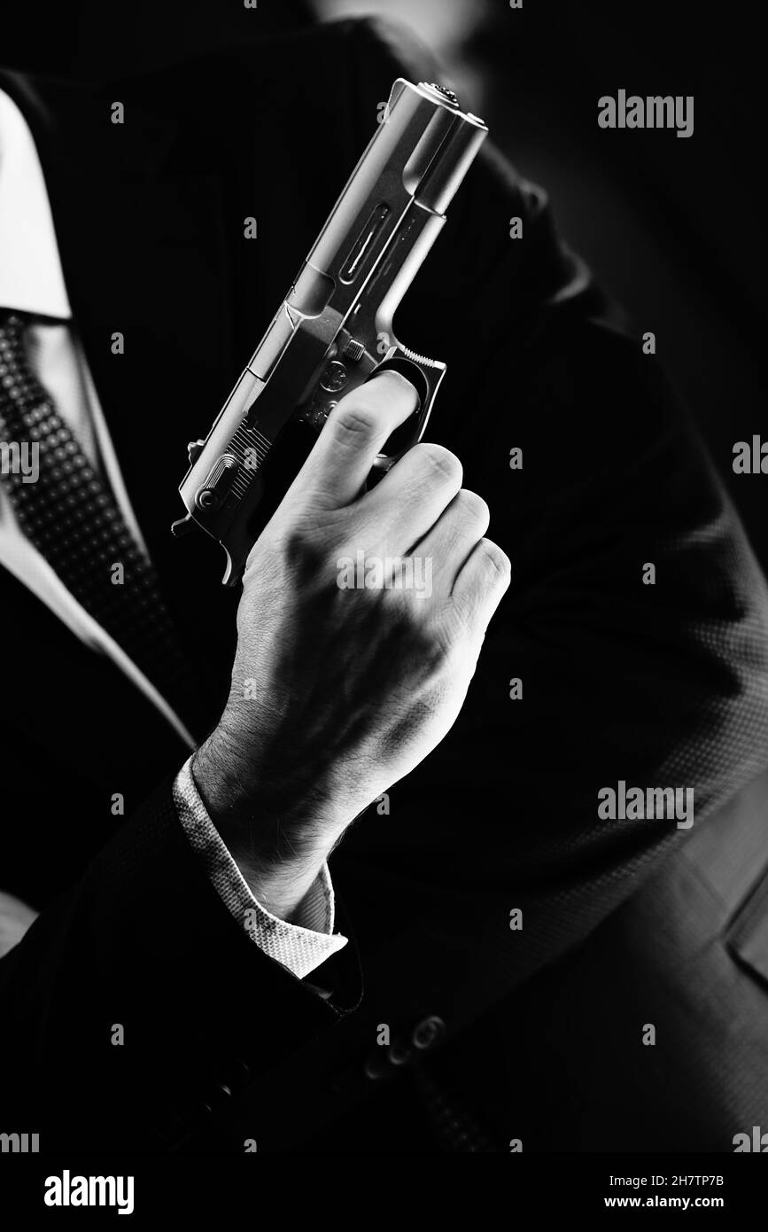 Homme bien habillé agent secret détective espion port combinaison et cravate tenant pistolet automatique. Banque D'Images