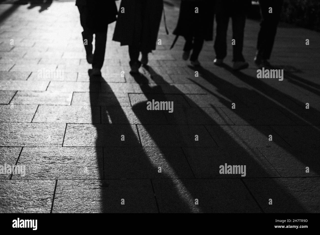 Prise de vue en niveaux de gris des ombres des personnes marchant dans la rue Banque D'Images