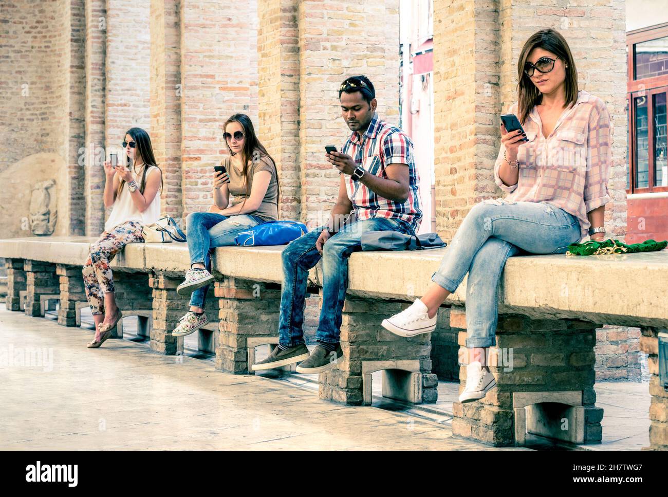 Groupe de jeunes amis multiraciaux utilisant un smartphone avec désintérêt mutuel - dépendance technologique dans le mode de vie réel Banque D'Images