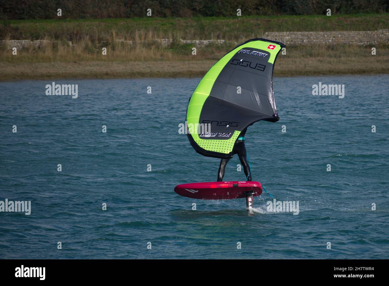 Planche à voile déferlant sur la rivière Adur à Shoreham en roulant à vitesse sur l'avion. Banque D'Images