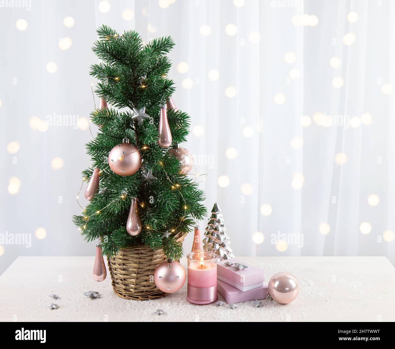 Décoration moderne en boules de couleur rose pastel accrochée à l'arbre de Noël dans le salon de la maison, avec cadeaux roses et bougie.CHRI de style rose pastel Banque D'Images