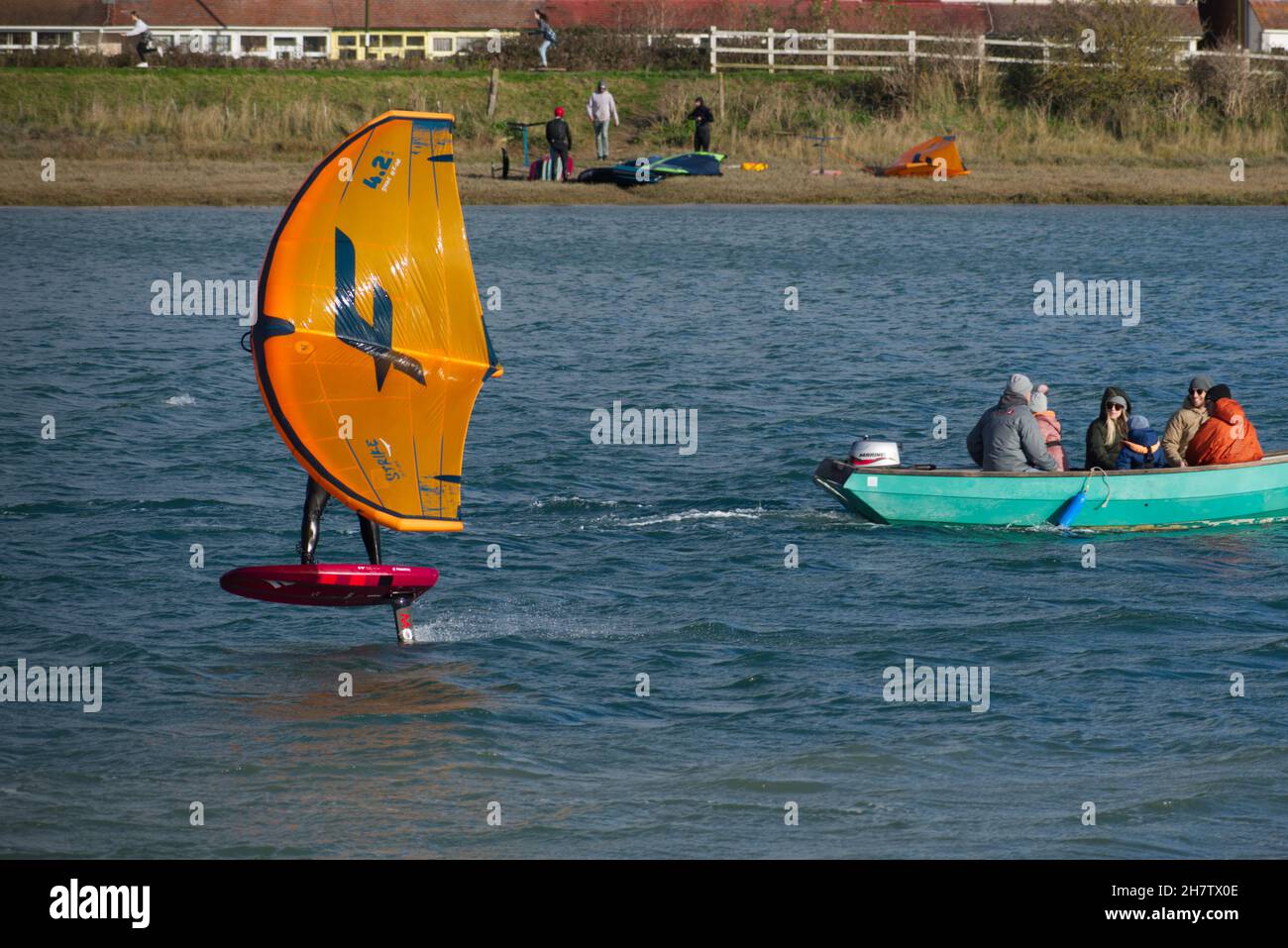 Personne sur une feuille d'aile à la vitesse passant un petit bateau sur la rivière Adur à Shoreham. Banque D'Images