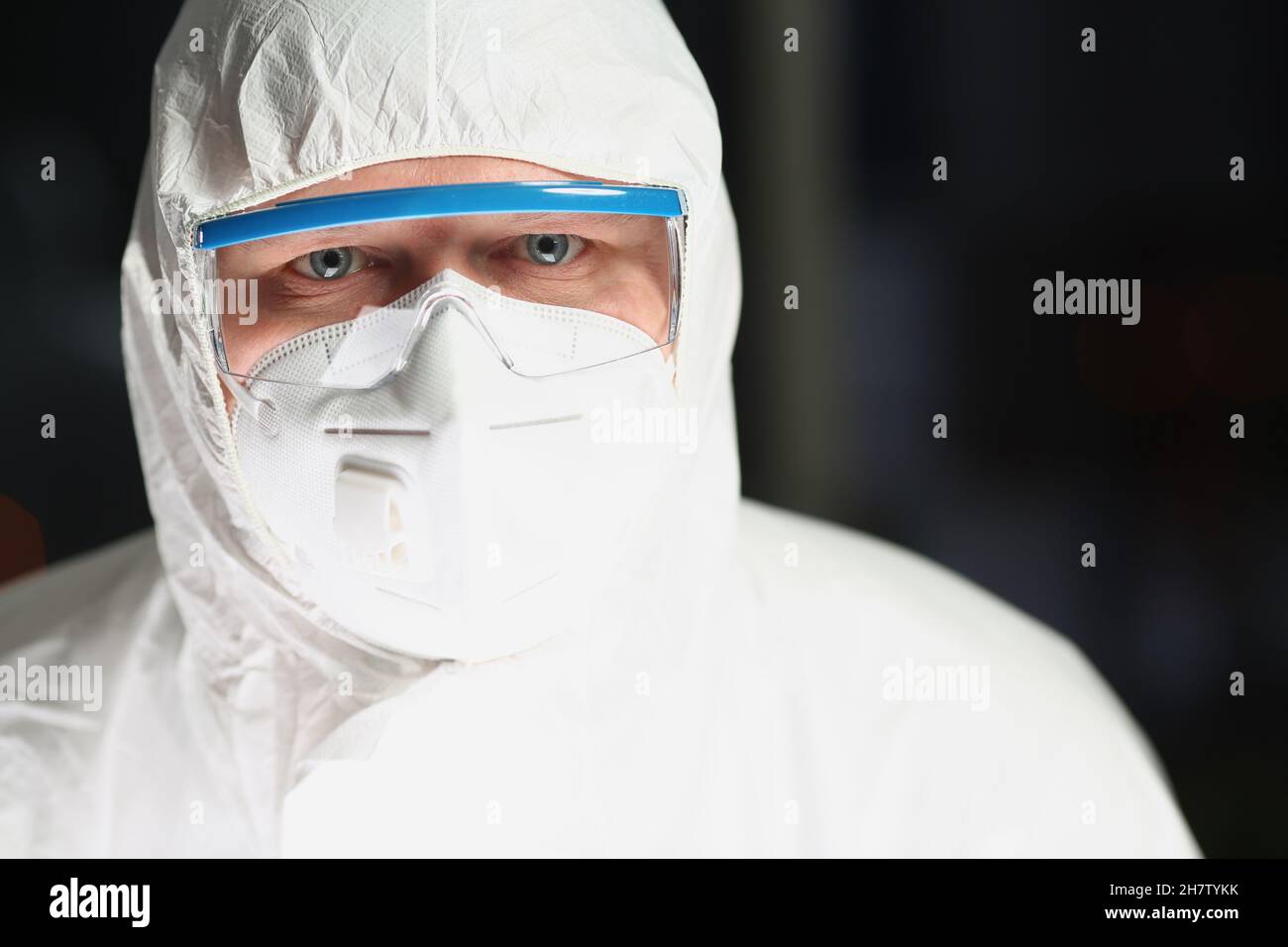 Travailleur en respirateur de protection et en combinaison blanche analysant l'expérience scientifique Banque D'Images