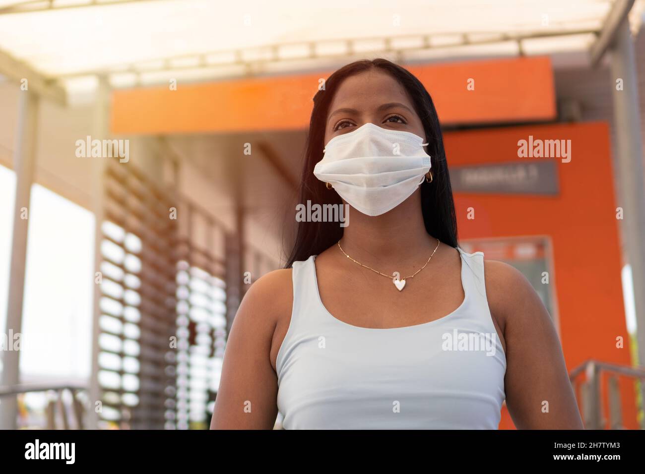 Jeune femme debout dans une gare routière avec un masque médical dans les temps COVID. Banque D'Images