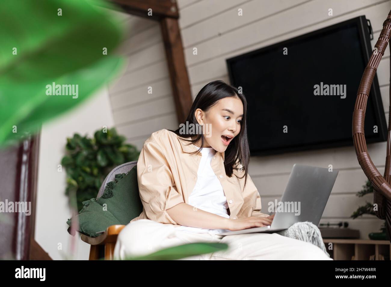 Jeune femme à la maison regardant son ordinateur portable avec stupéfait,  wow visage, choqué par la notification d'annonce sur l'ordinateur Photo  Stock - Alamy