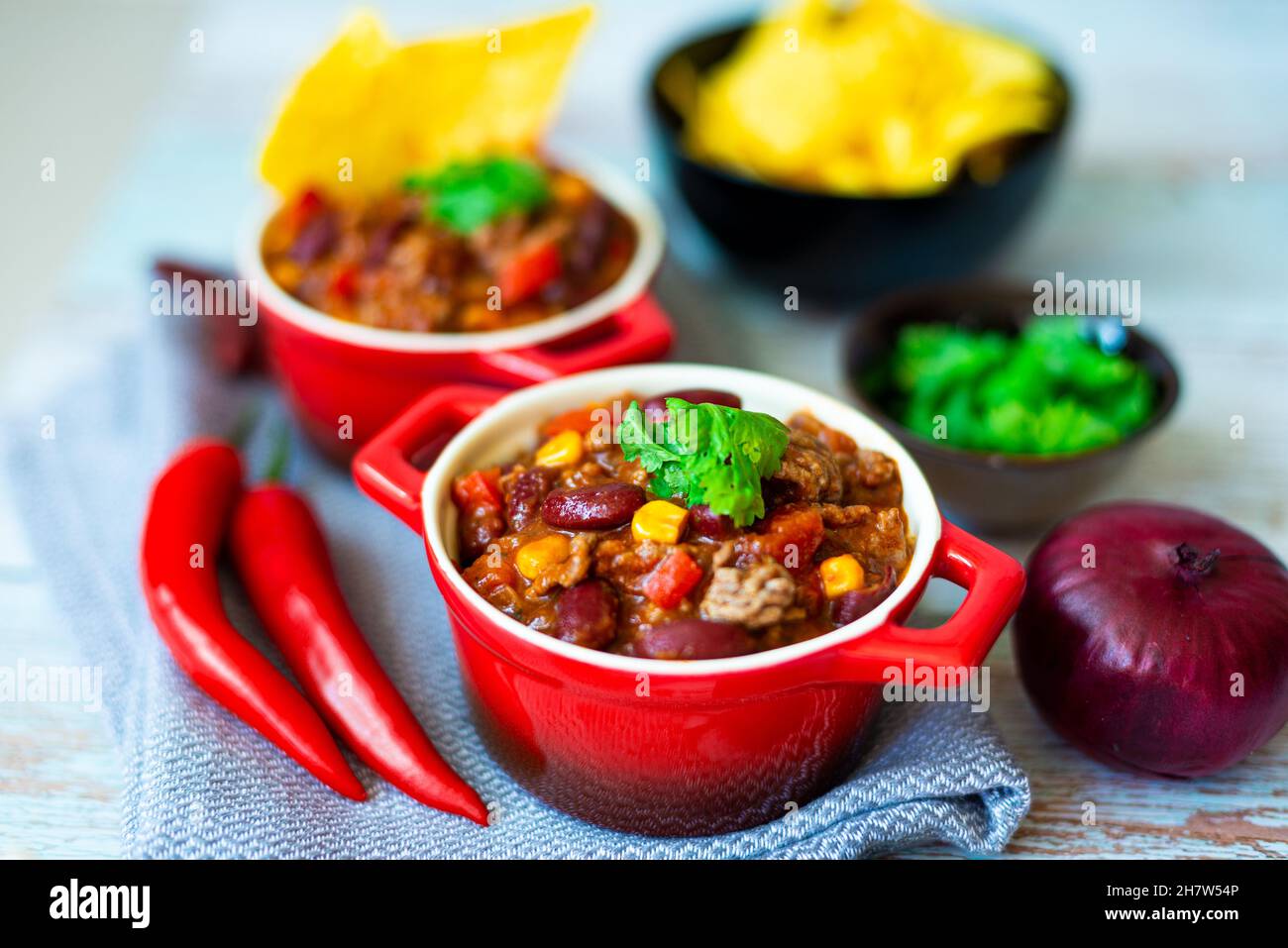 Délicieux Chili con carne dans des pots rouges servis avec une partie de croustilles tortilla Banque D'Images