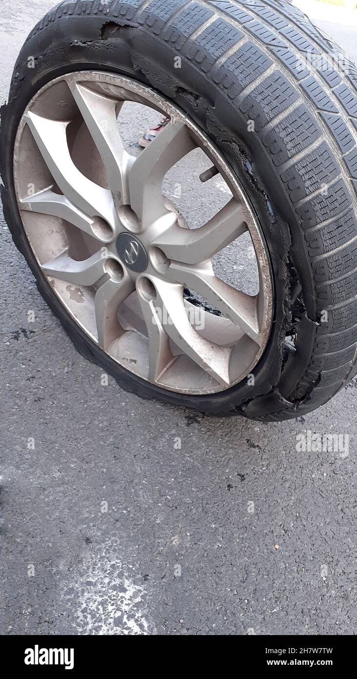 Pneu détruit sur une roue en alliage, les parois se sont désintégrées en raison de l'utilisation trop longue d'un pneu à plat.Le mur extérieur a été frotté sur le trottoir a échoué Banque D'Images