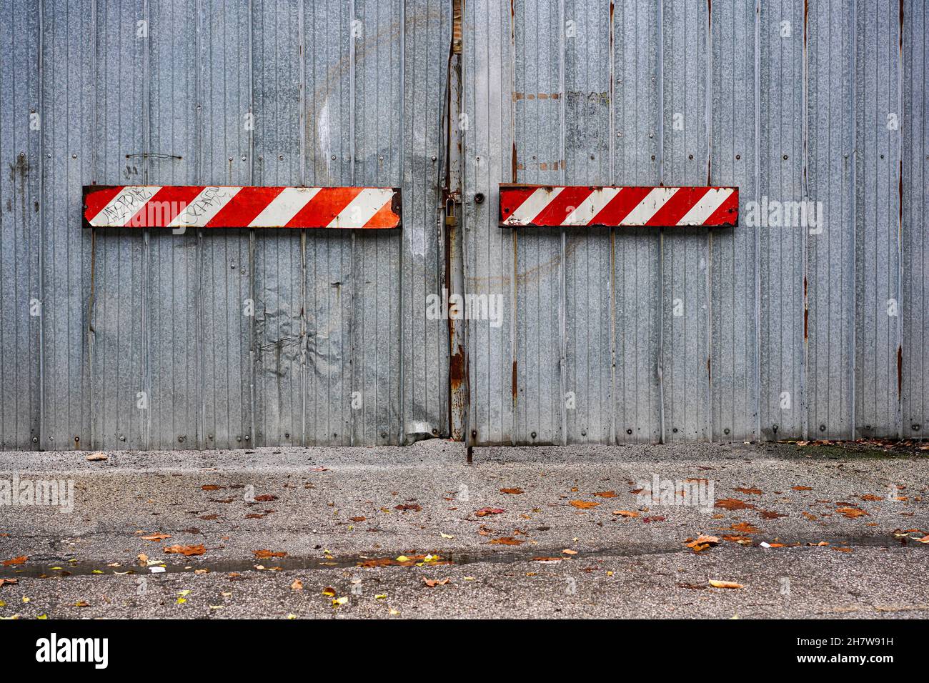 Longs panneaux d'avertissement rectangulaires blancs rouges sur une porte de garage de couleur grise. Banque D'Images