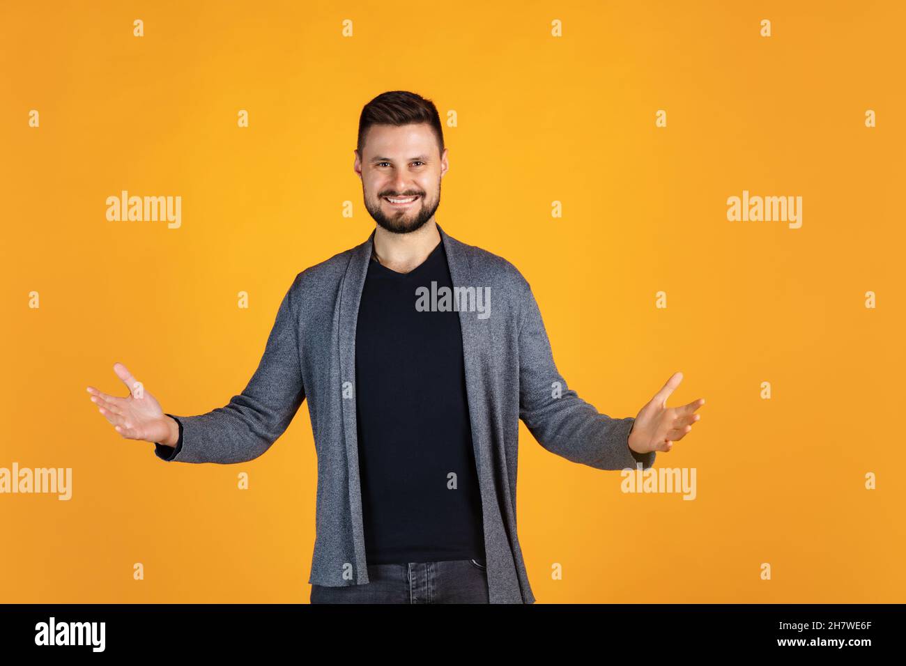 Portrait court de l'homme heureux et excité dans un gilet gris gaierposant entièrement isolé sur fond jaune Banque D'Images
