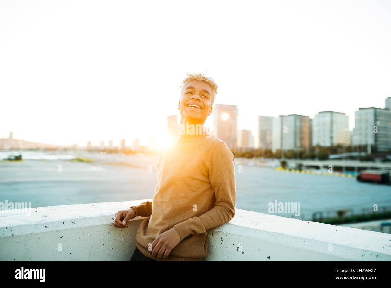 Portrait d'un jeune homme latino-américain debout au coucher du soleil sur un paysage urbain Banque D'Images