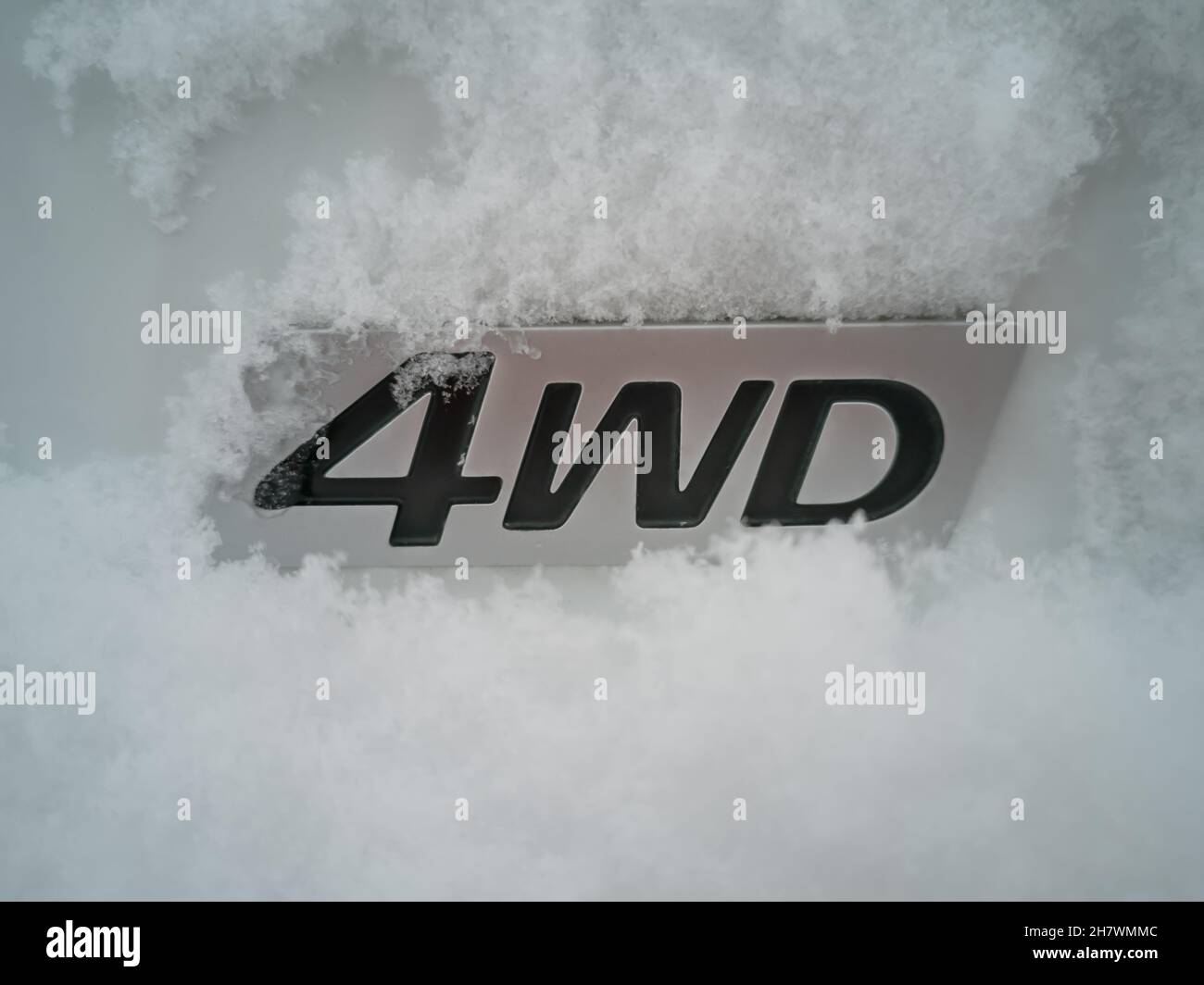 Abréviation 4wd - quatre roues motrices - sur une voiture blanche dans la neige dans le dos en hiver. Banque D'Images
