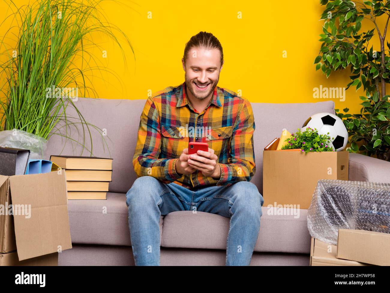 Photo de l'influenceur Guy sit canapé post nouvelles images plates médias sociaux porter chemise à carreaux isolé couleur jaune arrière-plan Banque D'Images