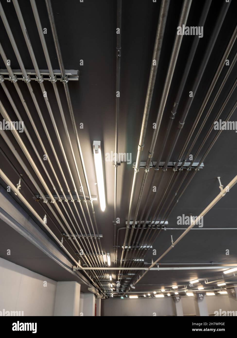 Installation ordonnée des conduits de tubes métalliques électriques galvanisés (EMT) au plafond du stationnement Banque D'Images