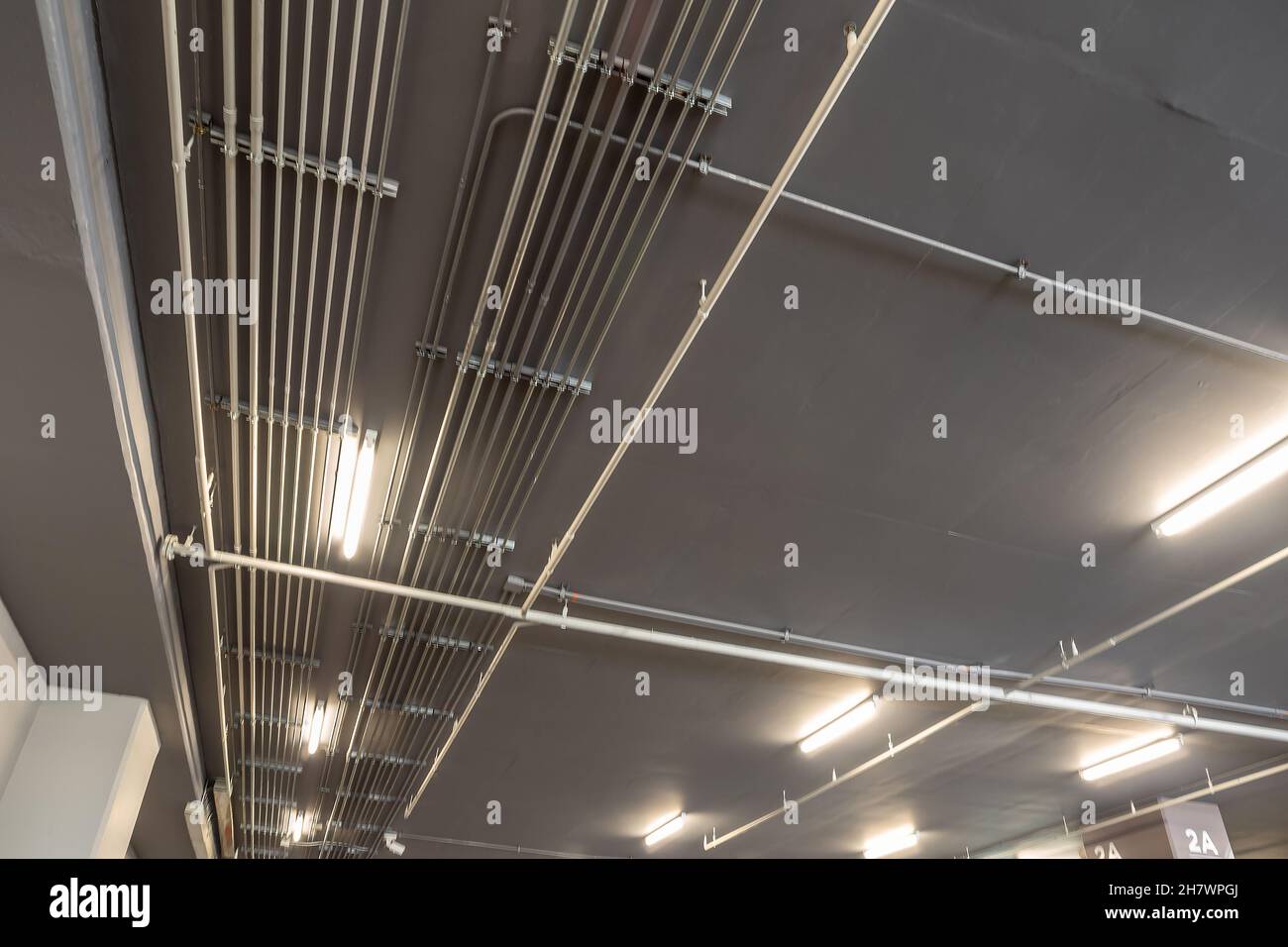 Installation ordonnée des conduits de tubes métalliques électriques galvanisés (EMT) au plafond du stationnement Banque D'Images