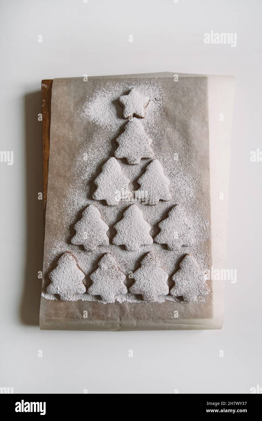 Arbre de Noël en pain d'épice parsemé de sucre en poudre sur parchemin.Composition créative, gros plan, espace de copie, vue de dessus Banque D'Images