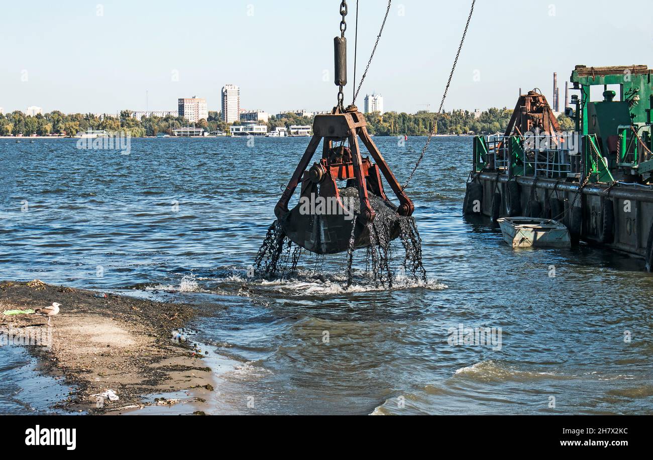 Nettoyage de l'île nouvellement formée des déchets industriels sur la rivière Dniepr par un dragueur.Problèmes environnementaux des rivières modernes.Concept d'écologie. Banque D'Images