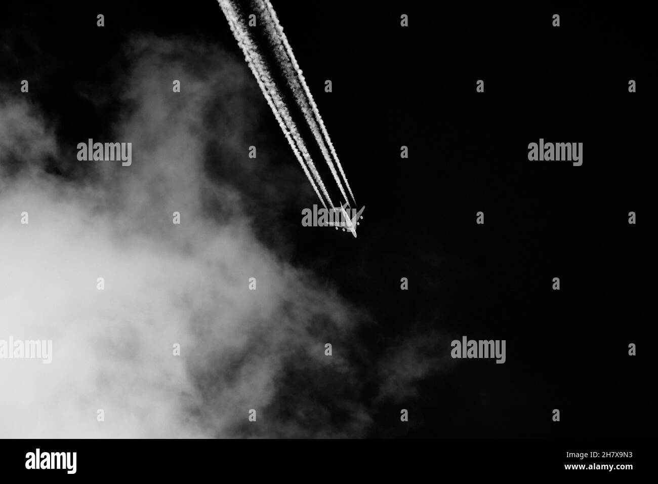 Les feuilles d'avion contrastals dans le ciel avec des nuages sur fond noir. Banque D'Images