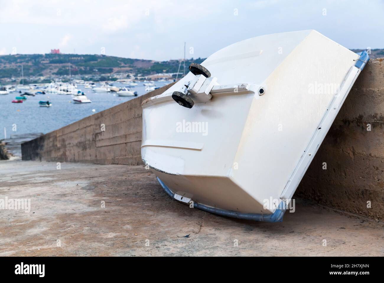 Un petit bateau blanc à roues repose sur le sol dans le port de Mellieha, à Malte Banque D'Images