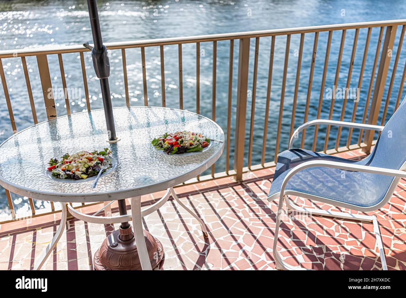 Deux assiettes à salade sur une table en verre et une balustrade sur le balcon, parasol à l'extérieur de personne à Miami, Florida intracoastal Waterway avec chaises et romantique v Banque D'Images