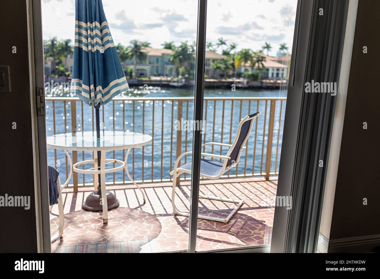 Table en verre et balustrades personne sur le balcon terrasse et parasol bleu dehors à Hollywood Beach, au nord de Miami, Floride avec des chaises et vue sur l'eau Banque D'Images