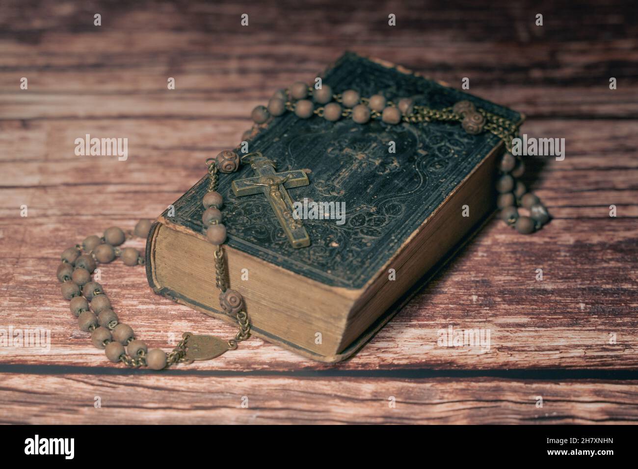 Grand studio de très vieux, ancienne Sainte Bible avec beaucoup d'ornements sur la couverture et les pages jaunes et vieux rosaire sur le bureau en bois vintage Banque D'Images