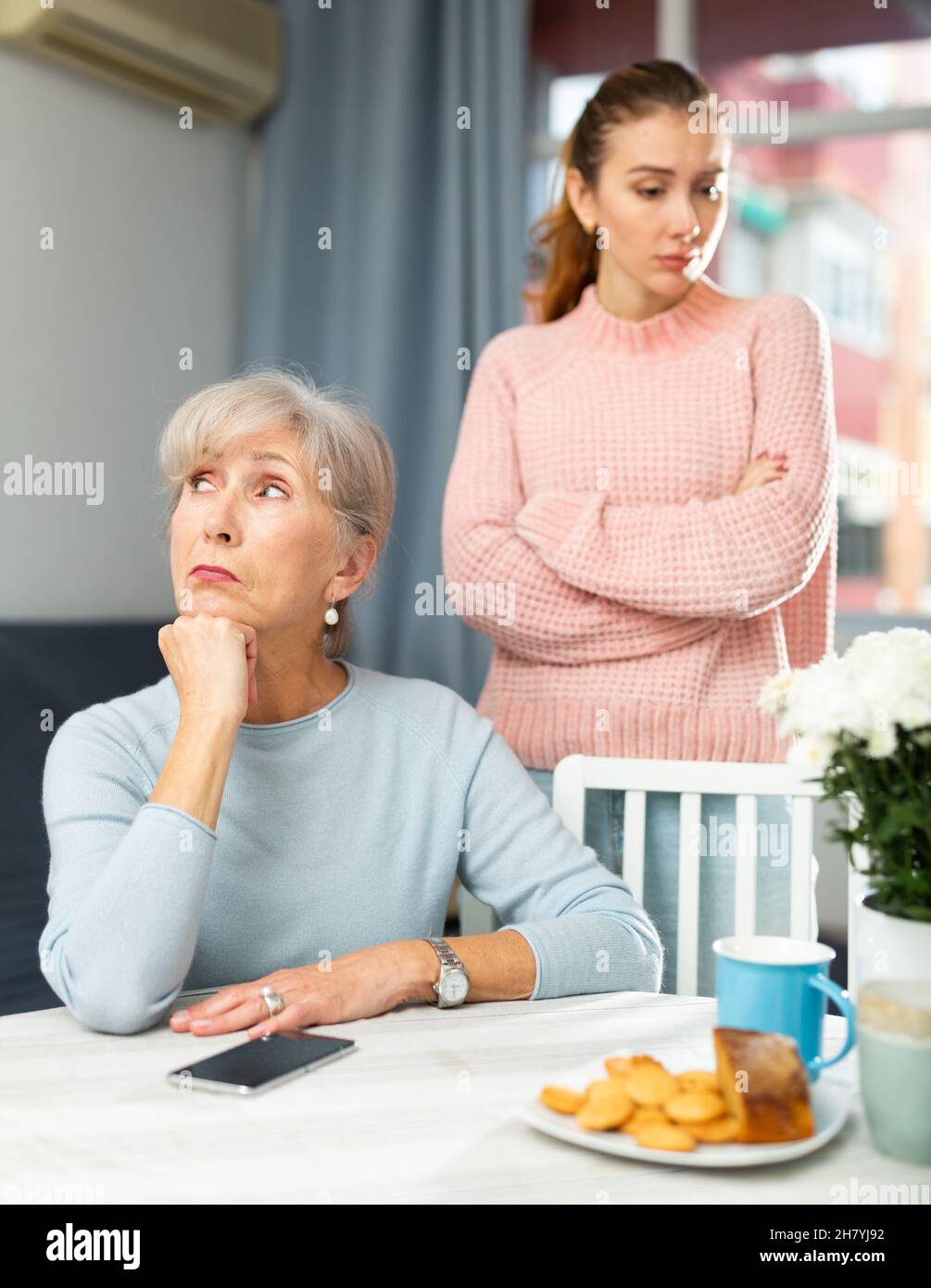 Bouleverser la femme âgée à la table après s'être querelle avec la fille adulte Banque D'Images