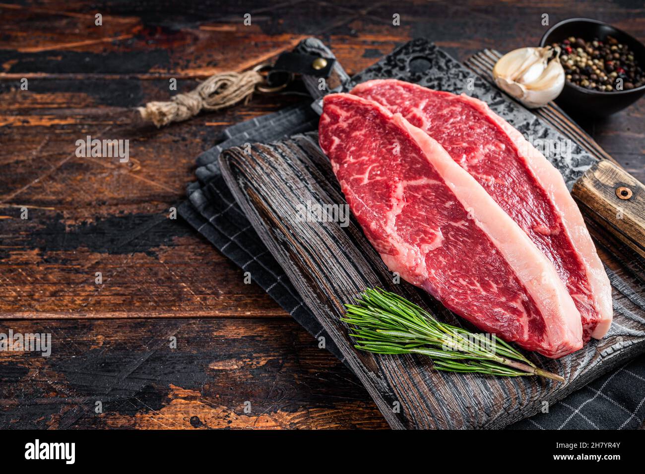 Steaks de viande de bœuf sur le dessus de la cicloine crue sur le butboard avec le cale à viande. Arrière-plan sombre. Vue de dessus. Copier l'espace Banque D'Images