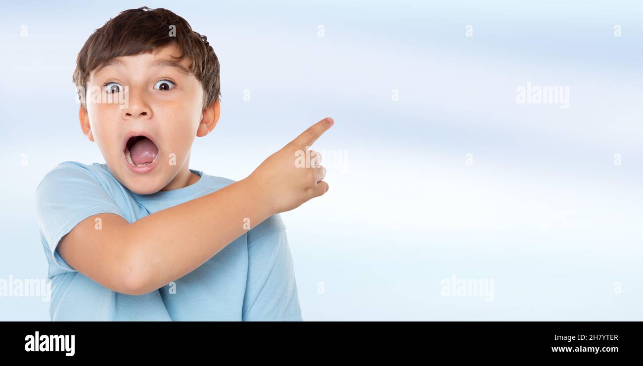 Enfant étonné enfant petit garçon surpris pointant sur la publicité publicitaire avec espace de copie de copyspace latin Banque D'Images