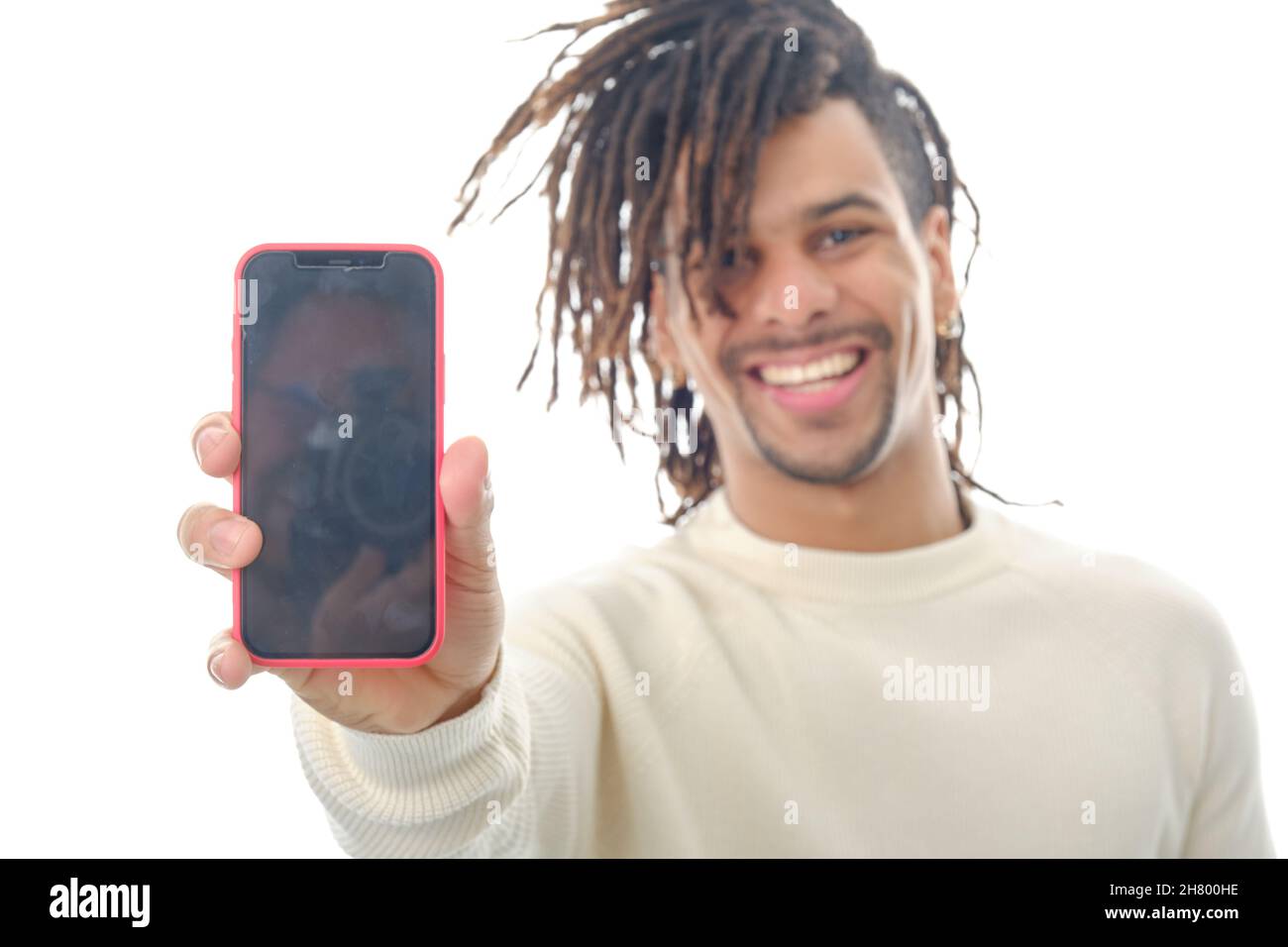 Homme souriant montrant un téléphone portable avec écran vide à la caméra tout en se tenant sur un arrière-plan isolé. Banque D'Images