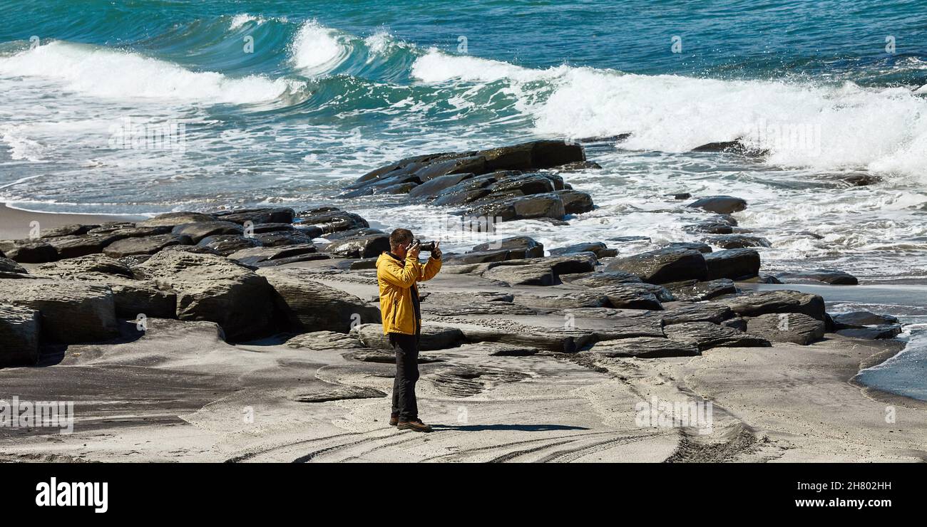 Un photographe masculin prend des photos sur fond d'une magnifique baie.Le rétroéclairage et un grand espace de ciel et de baie créent une atmosphère inhabituelle Banque D'Images