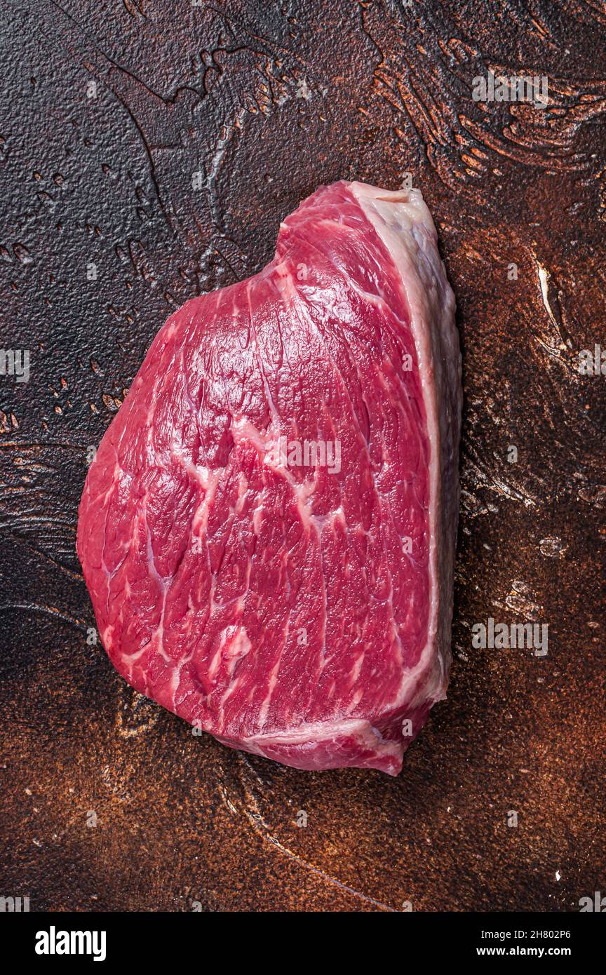 Bœuf cru coupé ou steak de viande de sirloin sur la table de boucher. Arrière-plan sombre. Vue de dessus Banque D'Images