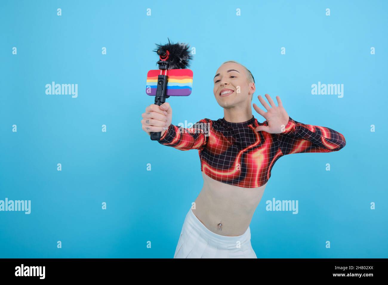 Personne d'influence sociale souriante et heureuse, non binaire, qui se connecte en ligne avec un téléphone mobile. Banque D'Images