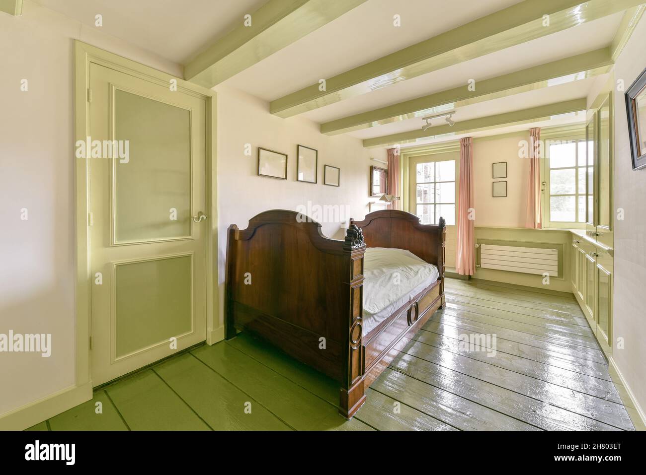 Lit en bois dans une chambre lumineuse avec fauteuil et intérieur rétro dans l'appartement Banque D'Images