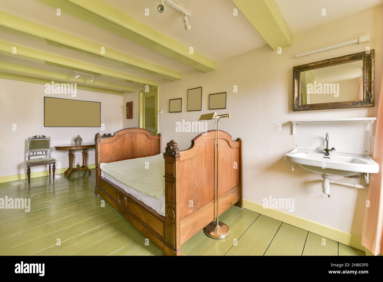 Lavabo blanc placé au mur avec miroir près du lit en bois dans la chambre lumineuse avec fauteuil et intérieur rétro dans l'appartement Banque D'Images