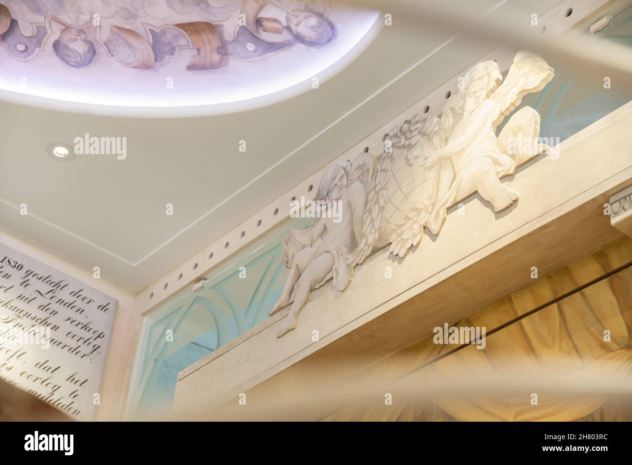 Depuis le dessous des anges décoratifs sur le mur près du plafond avec des éléments décoratifs dans la salle de lumière avec des lampes luminescentes dans l'appartement Banque D'Images