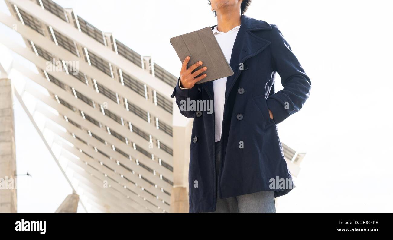 Femme positive avec une coiffure afro montrant un geste de paix tout en regardant la caméra avec la langue dehors près de la clôture en soirée Banque D'Images