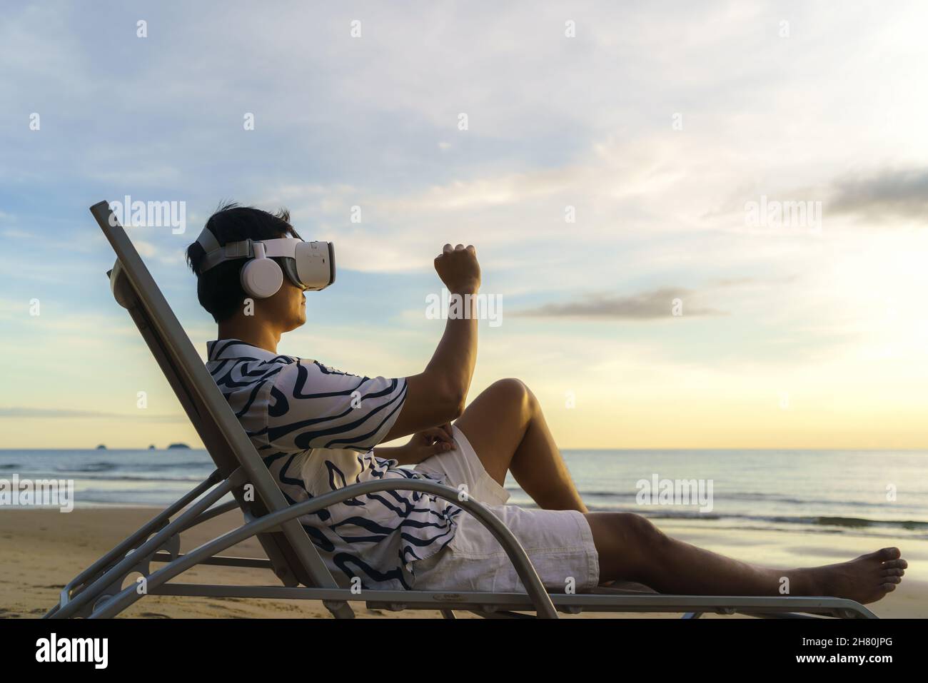 Jeune homme asiatique utilisant des lunettes de réalité virtuelle pour les réunions d'affaires sur la plage tropicale sur un magnifique fond de mer et de ciel Banque D'Images