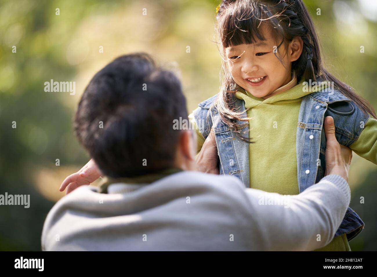 un jeune père asiatique embrasse une fille de 4 ans à l'extérieur dans un parc heureux et souriant Banque D'Images