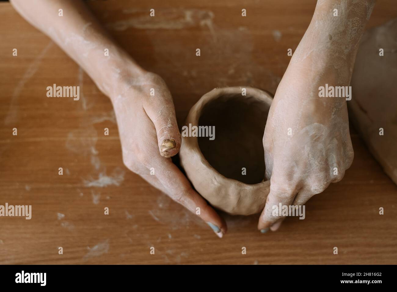 Vue de dessus des mains de femmes sculptant des ustensiles de l'argile. Banque D'Images