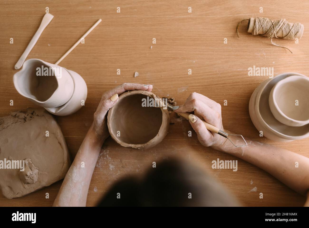 atelier de poterie concept d'art de l'argile. gros plan sur les mains d'un jeune céramiste avec un pot d'argile non cuit. les mains artisanales de travail tiennent une tasse d'argile Banque D'Images