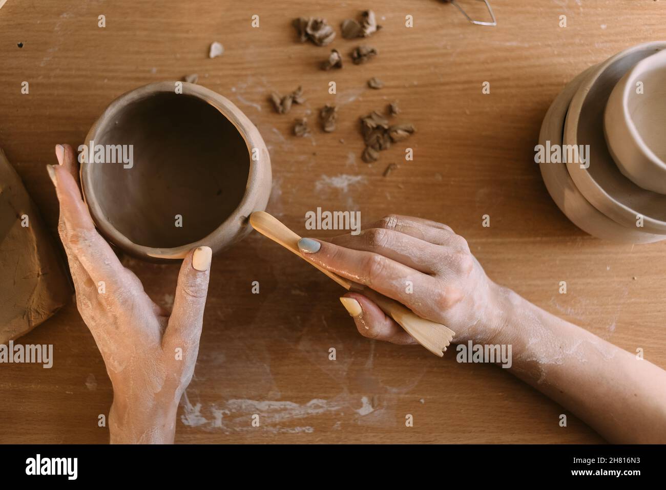 poterie et atelier avec concept d'art argileux. gros plan sur les mains d'un jeune céramiste avec un pot en argile non cuit. mains de travail artisanales Banque D'Images