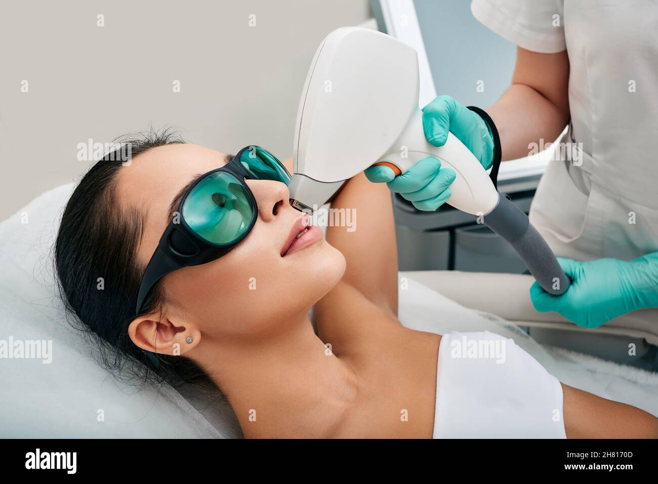 Belle femme portant des lunettes de protection lors de l'épilation au laser et de la zone des lèvres sur son visage dans un salon de beauté Banque D'Images