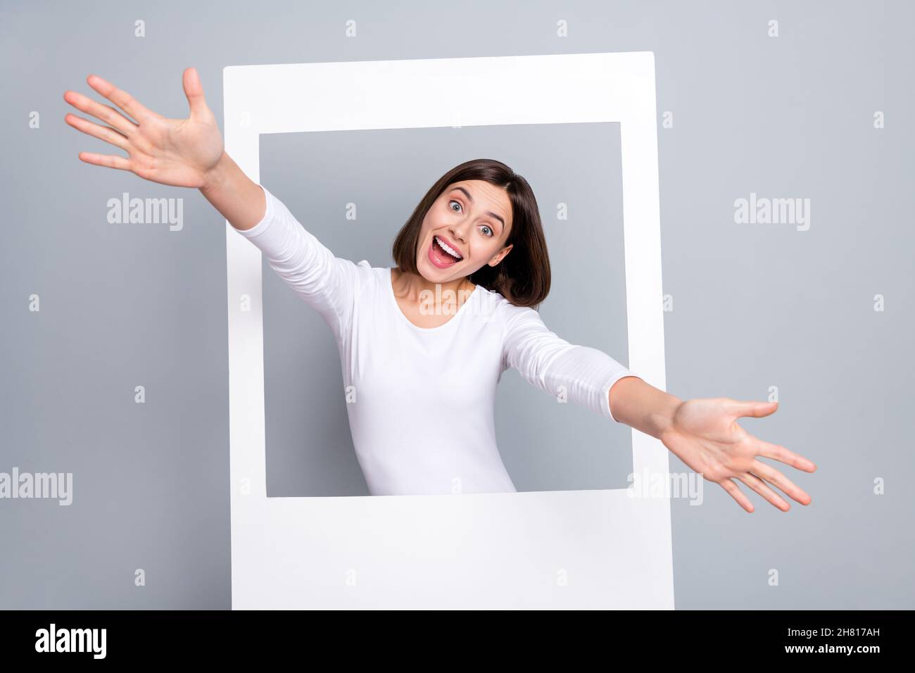 Photo de la jeune femme brune mignon apparaissent porter une chemise blanche isolée sur fond gris Banque D'Images