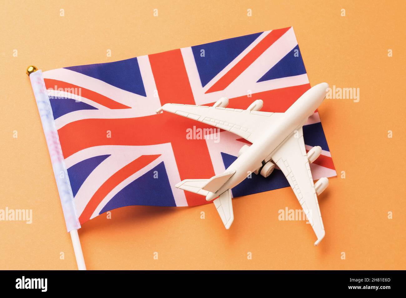 Drapeau de la Grande-Bretagne et avion jouet sur fond orange, concept de vol au Royaume-Uni Banque D'Images